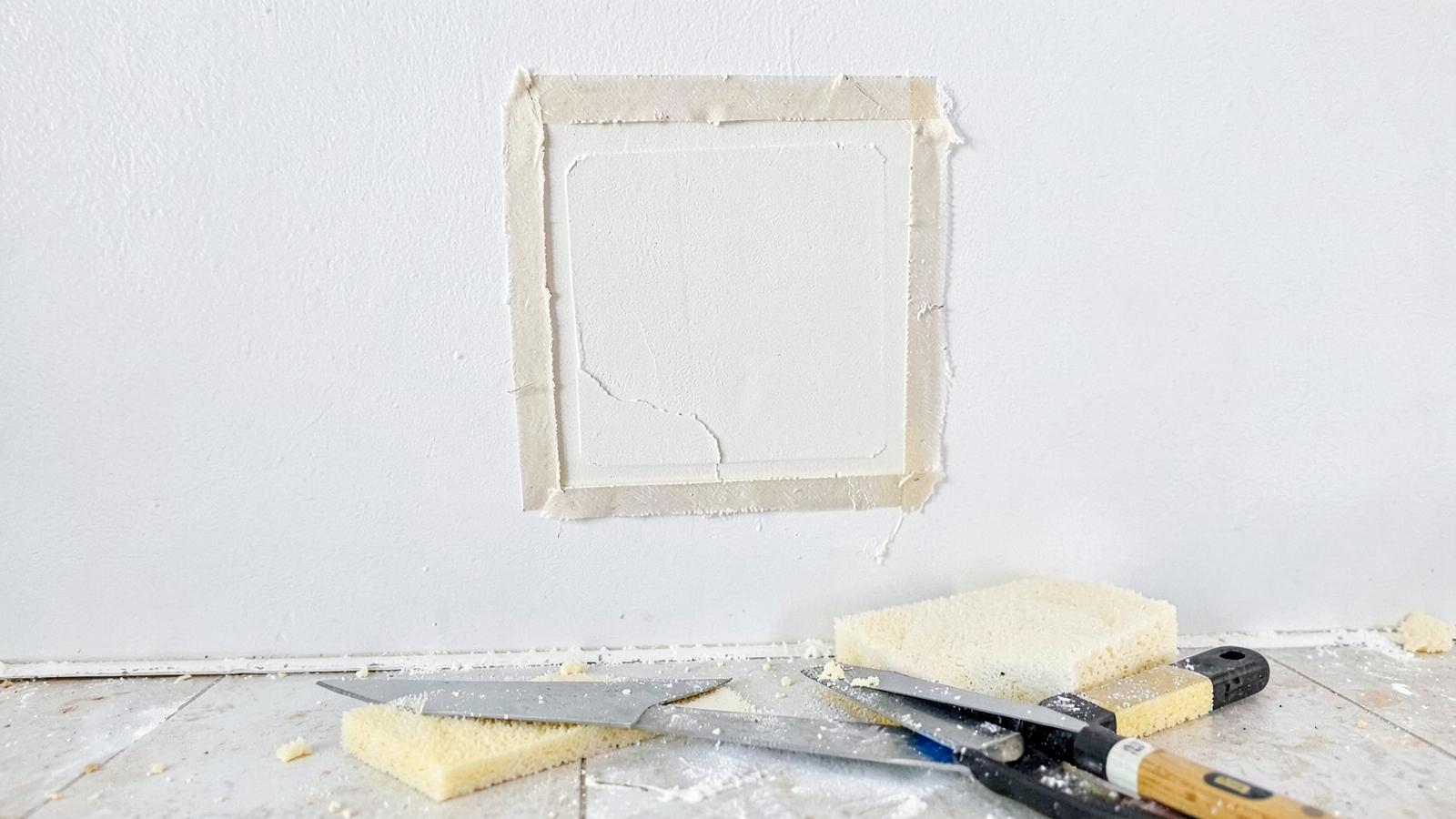 Square drywall patch with joint compound, taping knives, and sanding sponges
